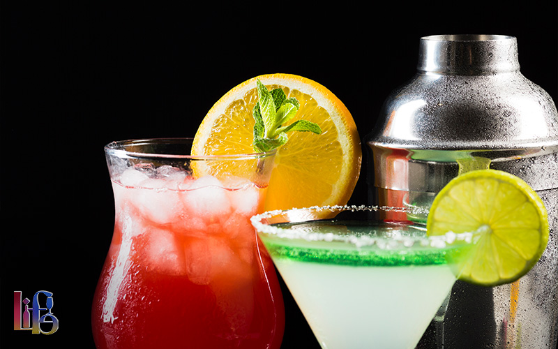 Close-up of vibrant summer cocktails next to a stainless steel shaker