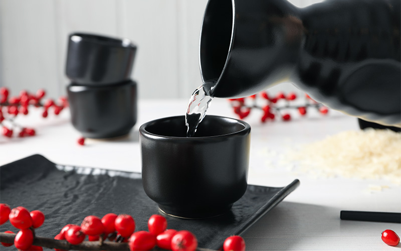 Close-up of Japanese sake poured into traditional ceramic cup.