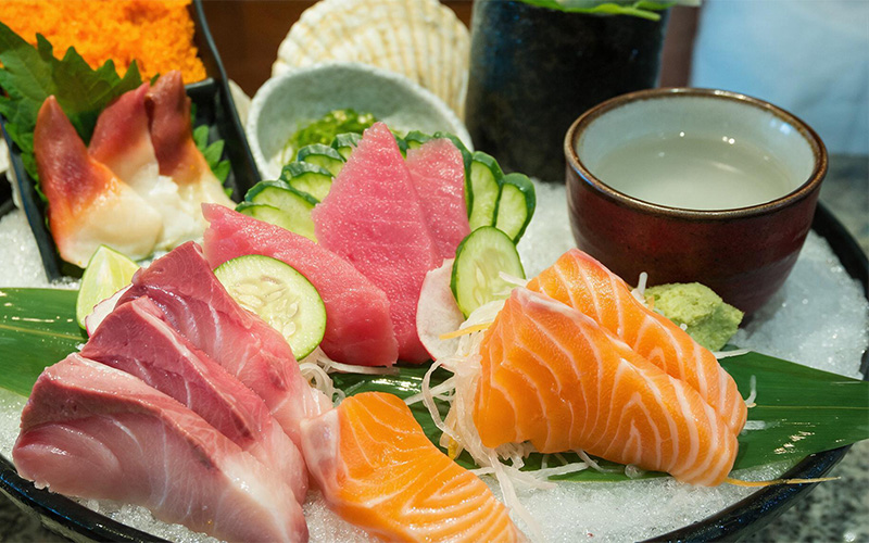 Fresh sashimi platter served alongside a cup of Japanese sake